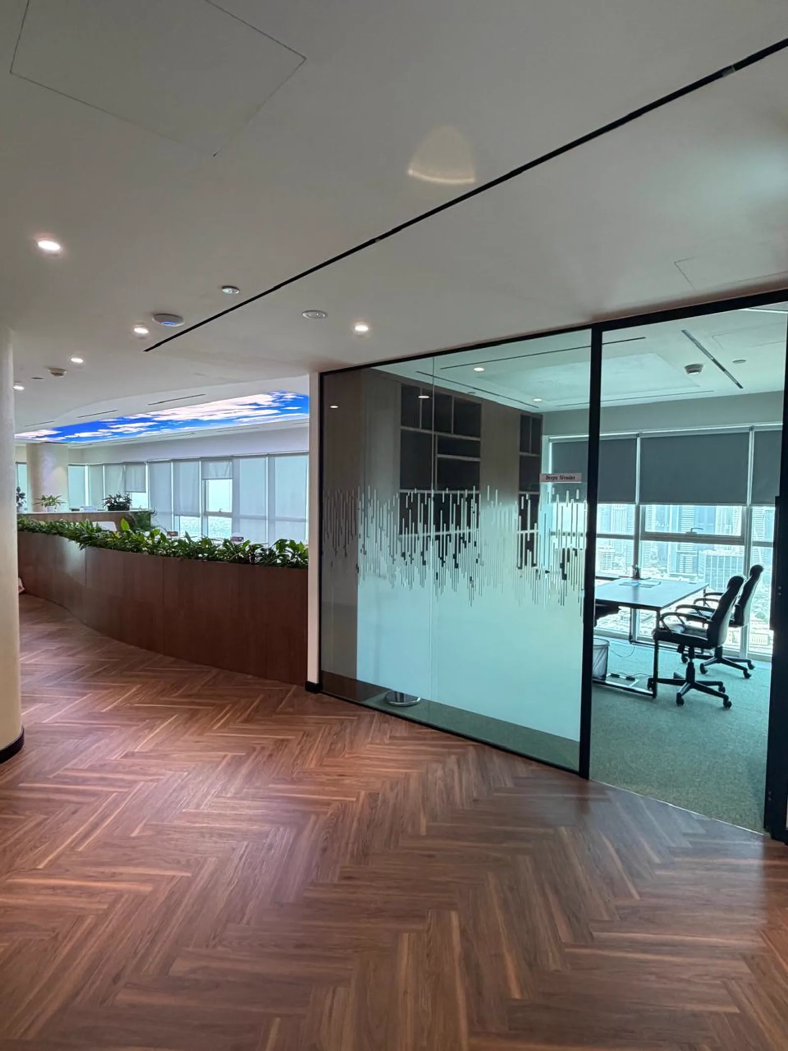 Frosted glass office partitions with etched graphics beside herringbone timber flooring